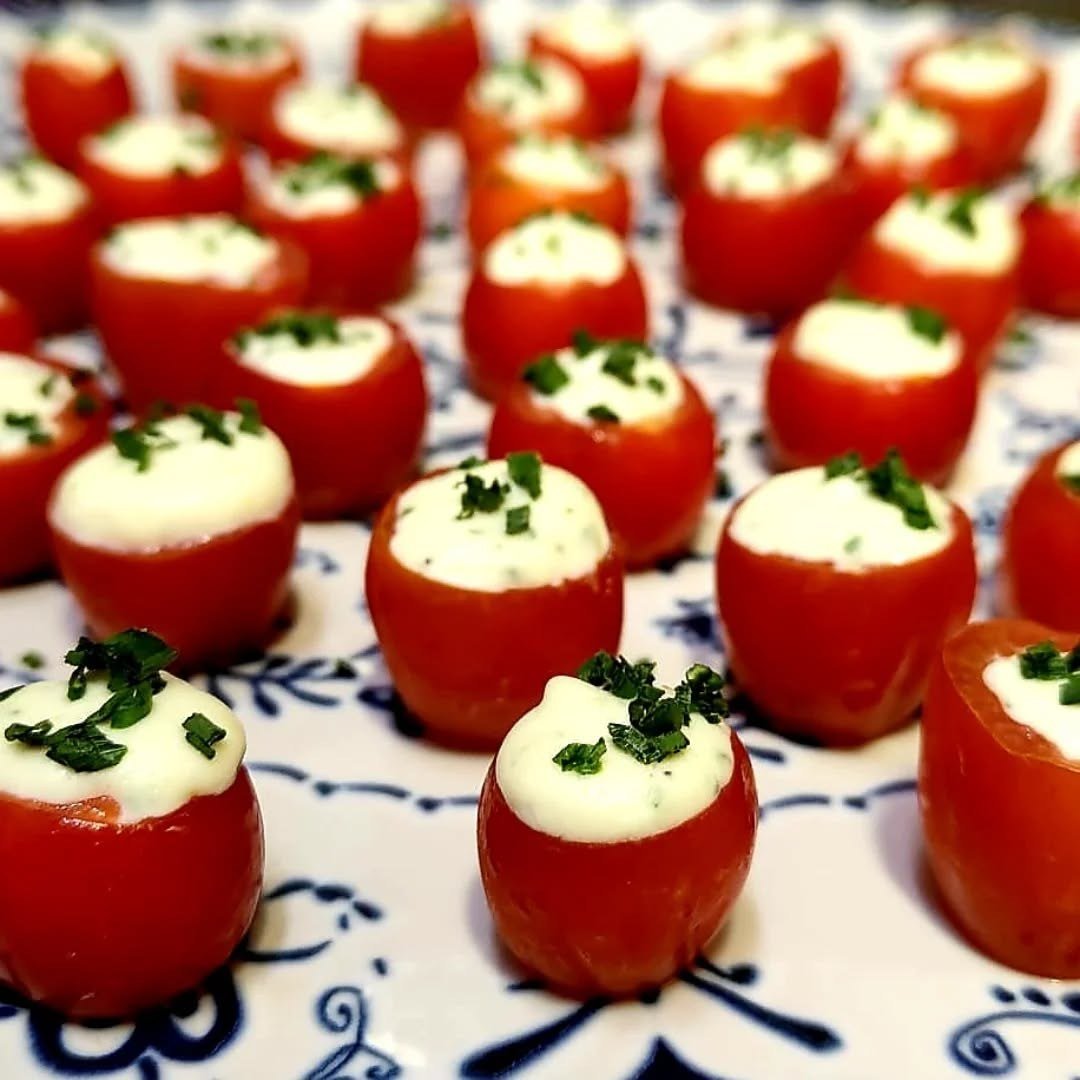 Tomates cereja recheados, com ervas por cima, num prato de azulejo azul e branco
